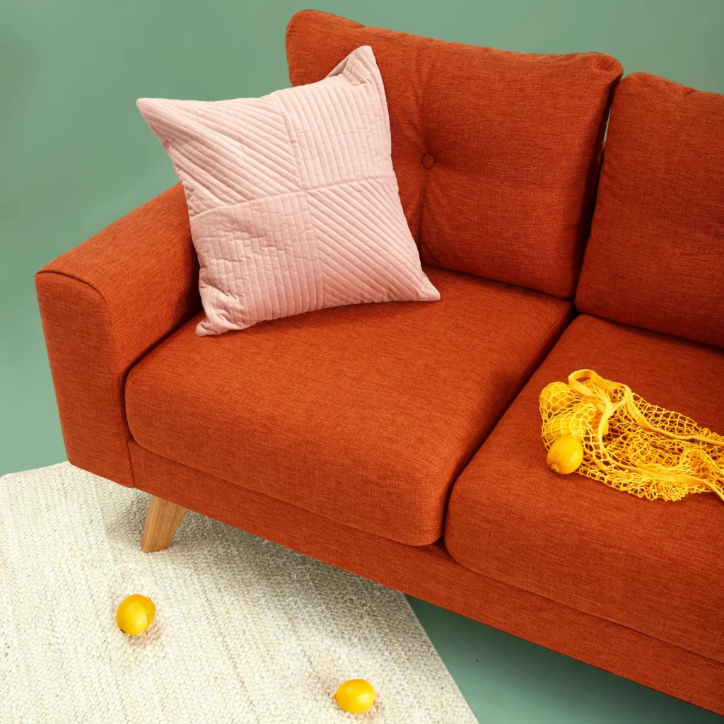 An orange sofa with pink square pillow The best furniture shop in Kozhikode